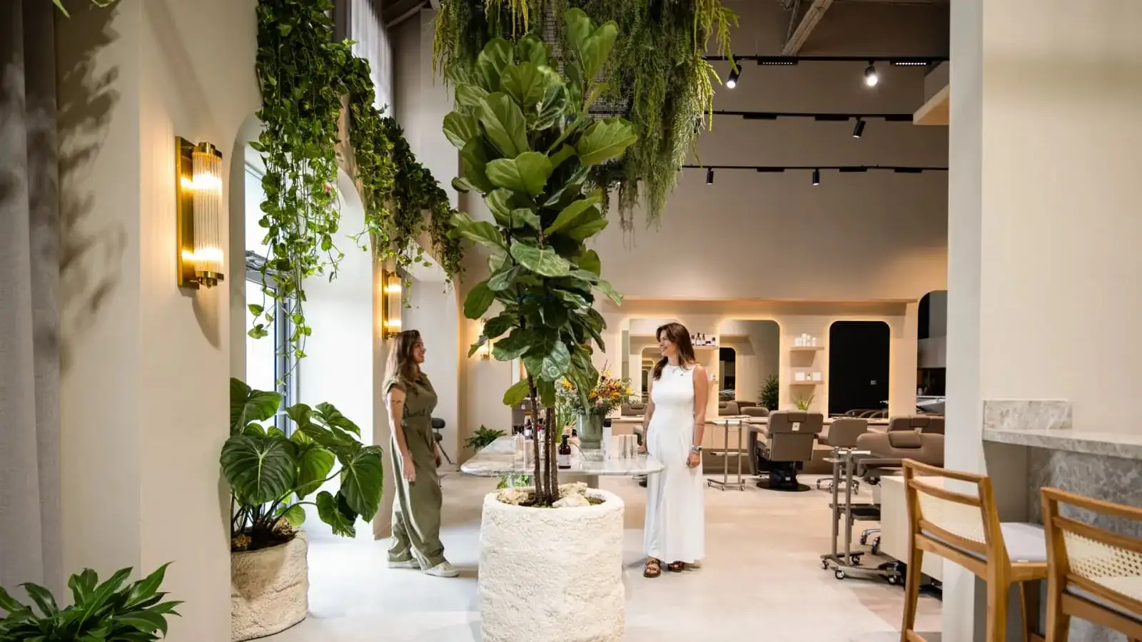 Luxury biophilic hair salon in Miami with lush greenery, arched doorways, and warm lighting — designed by Paula Ambrosio Interiors